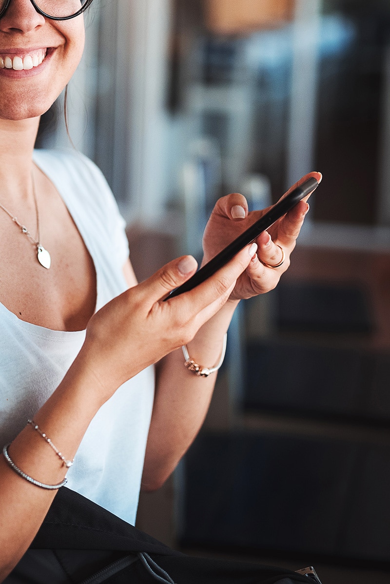 woman smiling while holding her phone