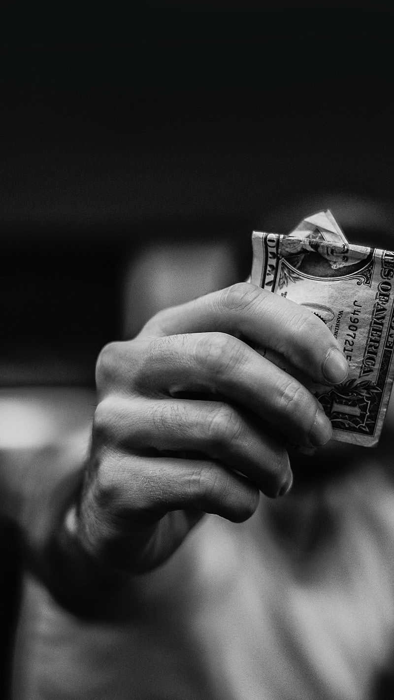 hand holding out one dollar bill in cash to negotiate a fair price