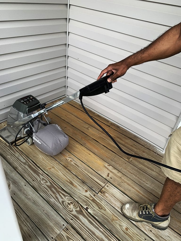 sanding porch using sander before applying waterproofing stain