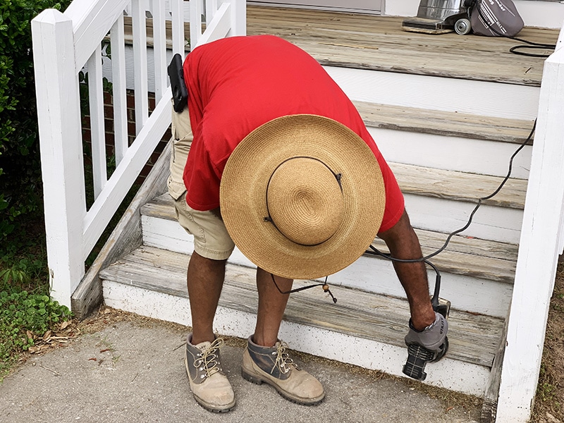 man in hat sanding stairs