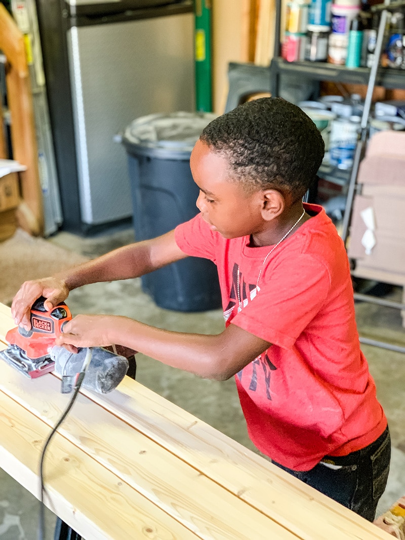 little boy sanding shelf