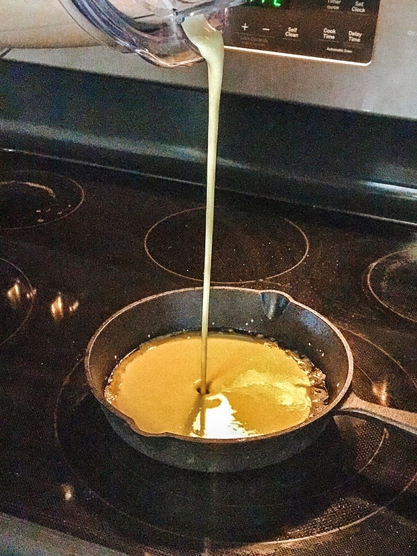 pouring dutch baby pancake batter in skillet