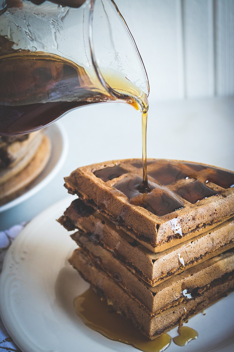 syrup being poured over stack of double chocolate banana waffles