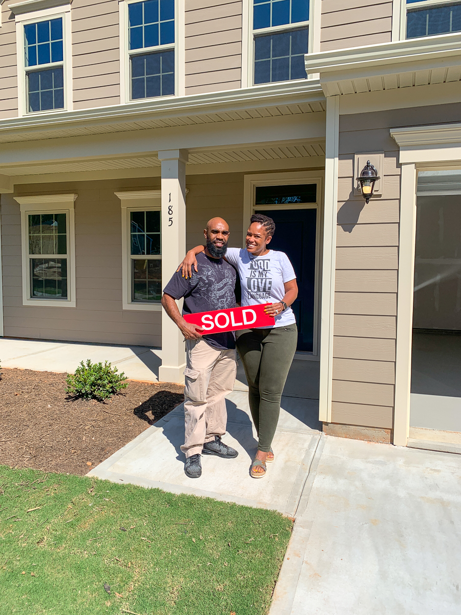 holding the sold sign in front of our ryan homes lehigh new build