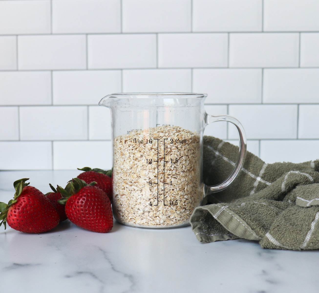 strawberries on white ceramic bowl beside clear glass of oatmeal
