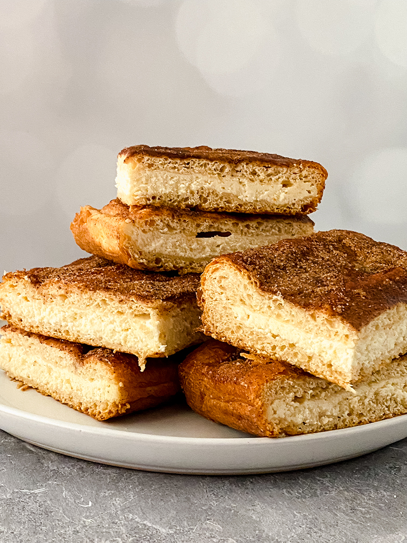 Churro cheesecake bars stacked on a plate