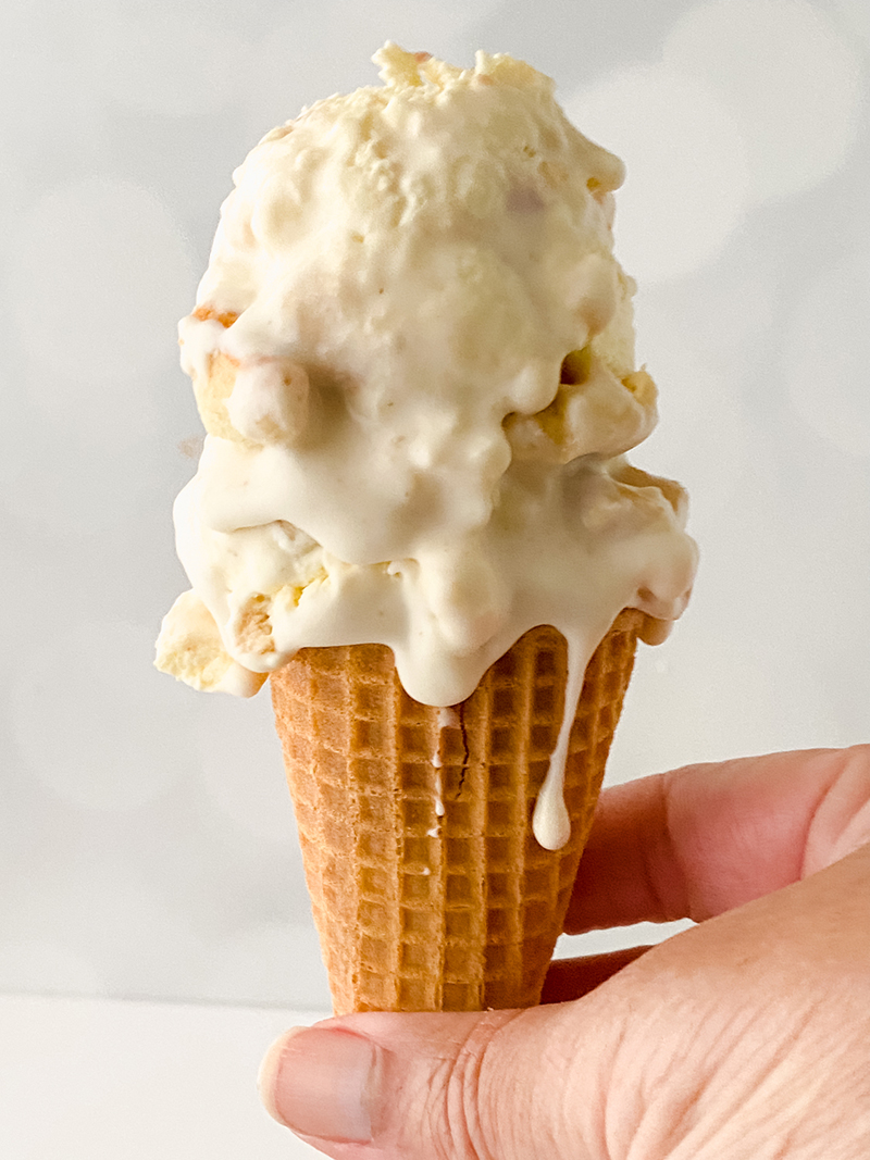 Banana pudding ice cream in cone being held in hand