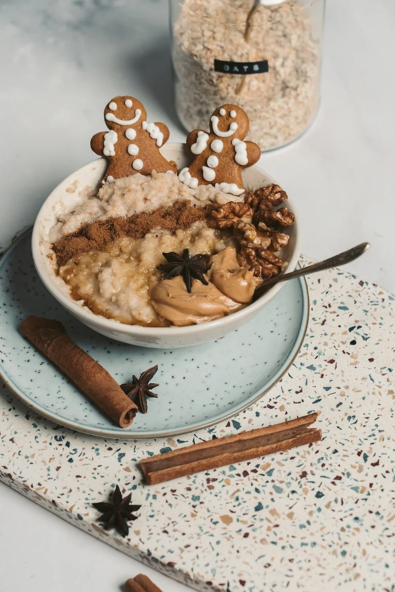 | Kenya Rae Oatmeal in a Bowl with toppings and cinnamon stick on the side